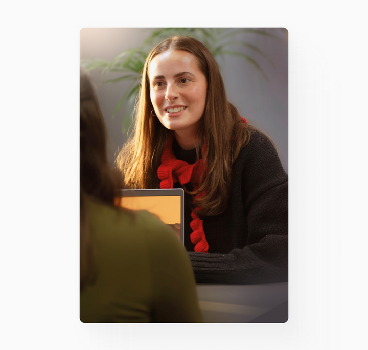 Young woman with long hair is interviewed in a sunny office room.