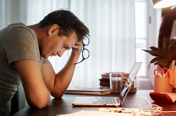 Man looking stressed whilst looking at a computer 